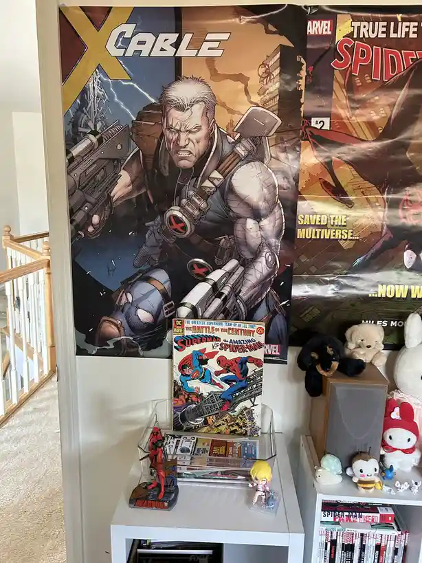 A room corner displays comic book posters, including one of Cable and another partially visible 'True Life Spider-Man'…