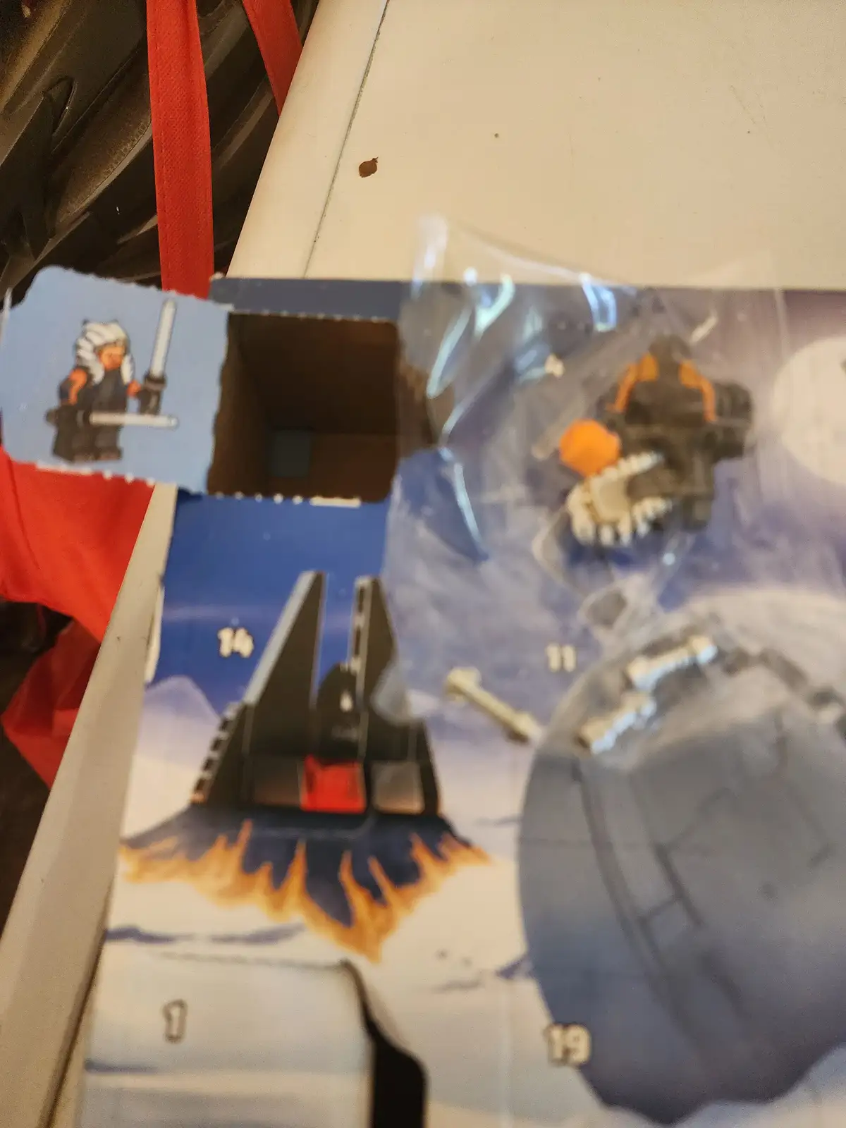 A close-up, slightly blurry photo shows the inside of an opened LEGO Star Wars Advent Calendar box. Visible are several…