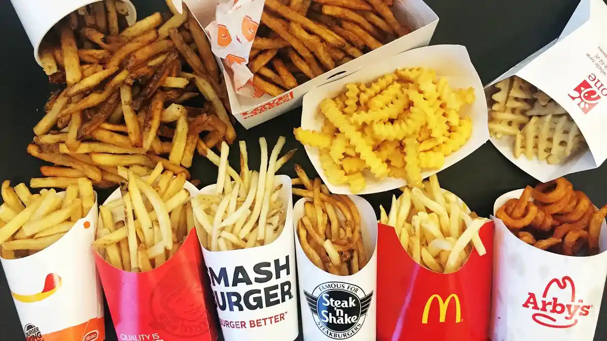 A flat-lay photo shows numerous fast-food french fry containers from different chains like Burger King, Smashburger, Steak…