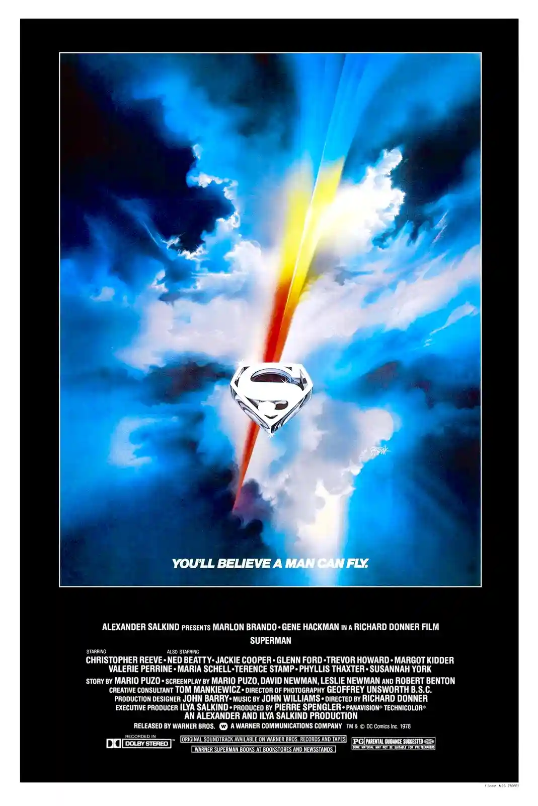 The image is the iconic 1978 movie poster for 'Superman,' featuring a silver Superman logo at the center, pierced by a…