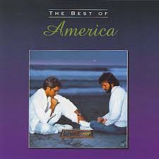 An album cover titled 'The Best of America' shows two men in white shirts sitting on a beach, one holding a guitar while the…