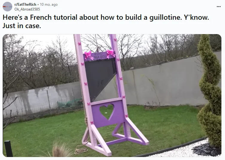 A purple-painted guillotine stands in a grassy backyard, decorated with pink bows and a heart-shaped cutout on its base. The…