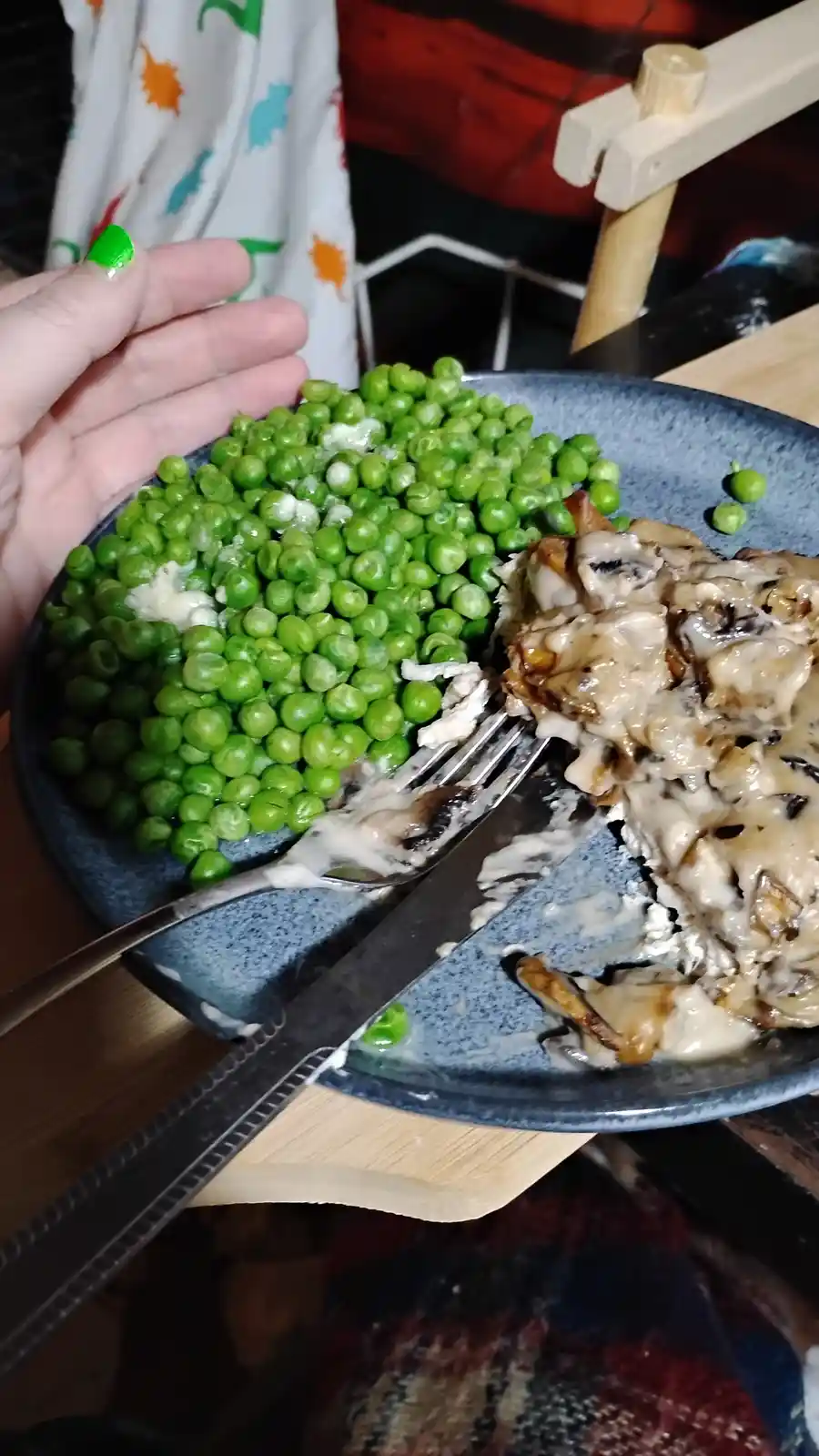 A close-up photo shows a blue speckled plate with a large portion of bright green peas and a smaller portion of creamy…