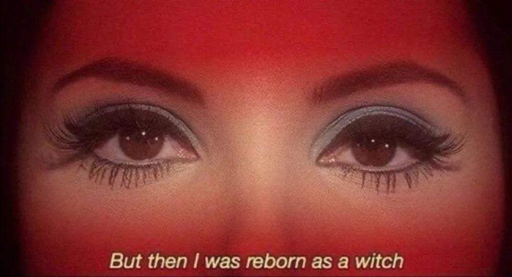 A close-up shot of a woman's eyes with heavy makeup, including dark eyeliner and long lashes, set against a red-lit…