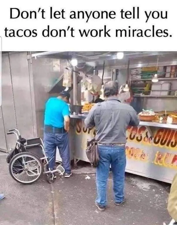 Two men stand at a taco food cart; one in a blue shirt leans over the counter, while the other in a gray shirt stands beside…