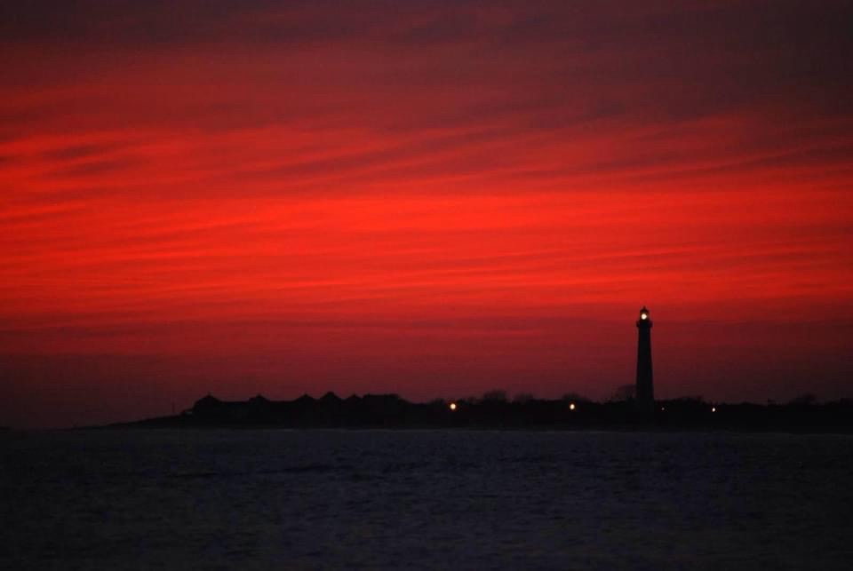 A dramatic red sunset over water with a lighthouse silhouette on the horizon. The overlaid text reads 'i'm not a fan of the…