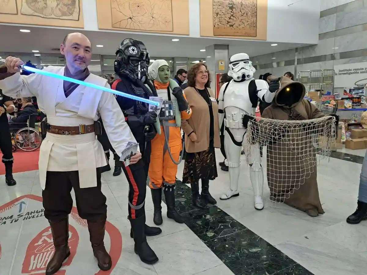 A group of people dressed as Star Wars characters, including a Jedi with a blue lightsaber, a Stormtrooper, a green-skinned…