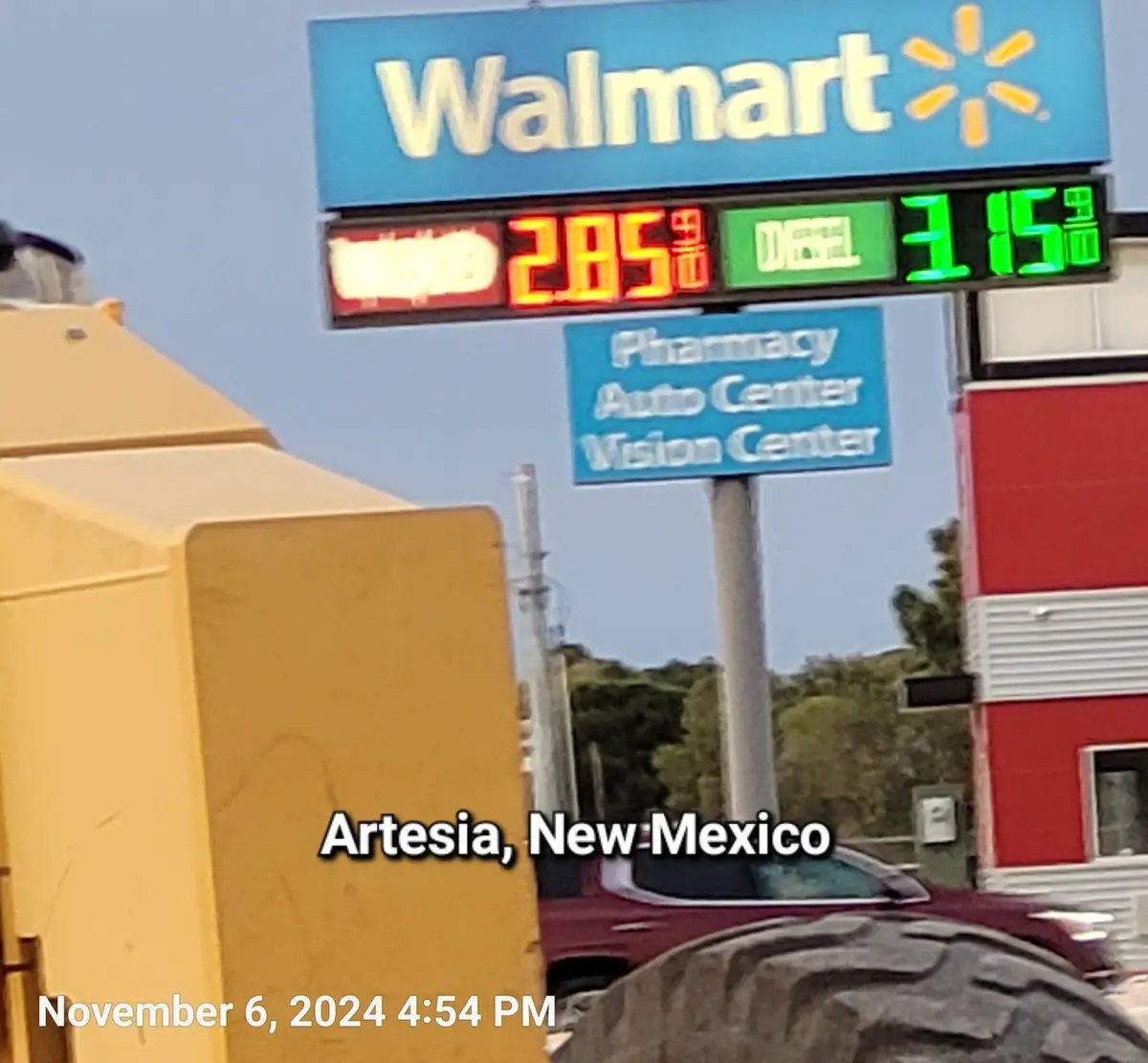 A photo of a Walmart gas station sign showing diesel at $3.15 and regular at $2.85, with a yellow vehicle partially…