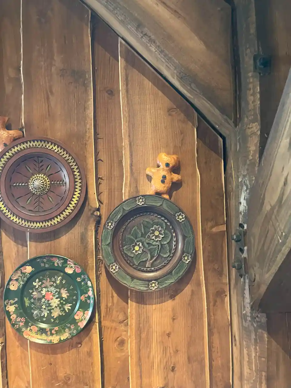 Three decorative plates hang on a rustic wooden wall, one topped with a small gingerbread man figurine. The overlaid text…