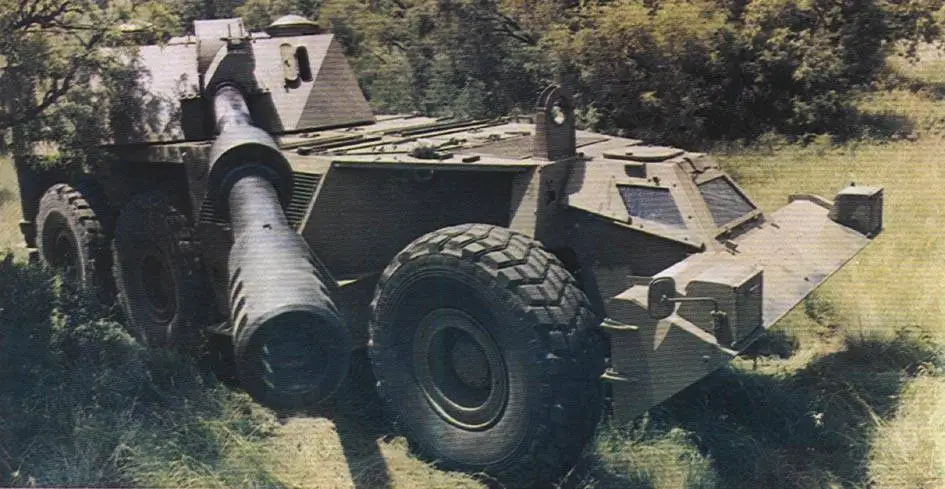 a military armored vehicle with a massive, oversized cannon mounted on its front, parked in a grassy field with trees in the…
