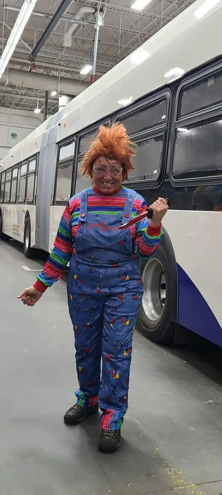 A person dressed as the horror character Chucky, complete with orange wig, striped shirt, denim overalls with 'Good Guys'…