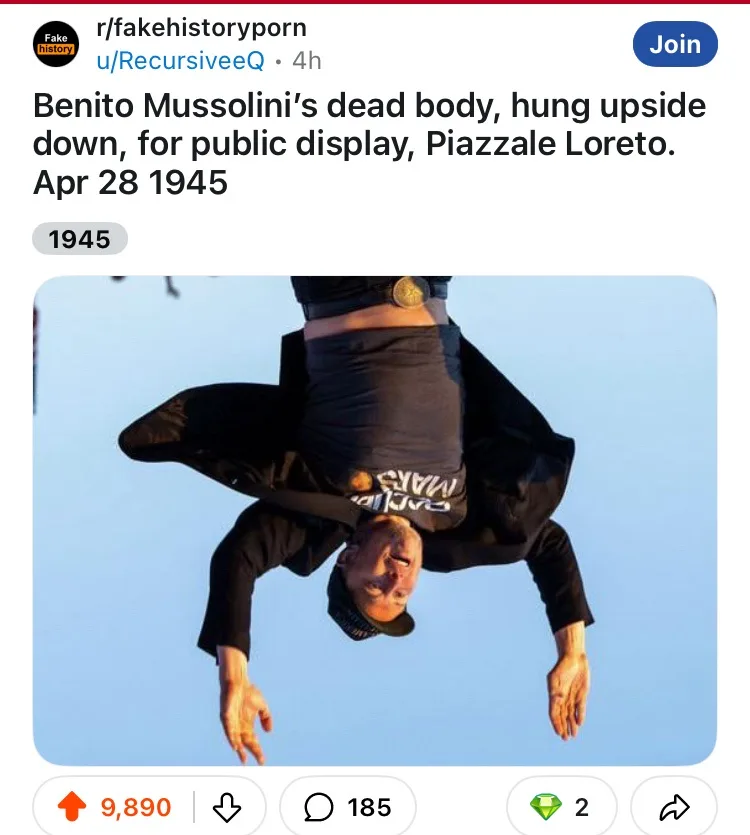 A man is photographed hanging upside down against a clear blue sky, wearing a black jacket, black t-shirt with white text…