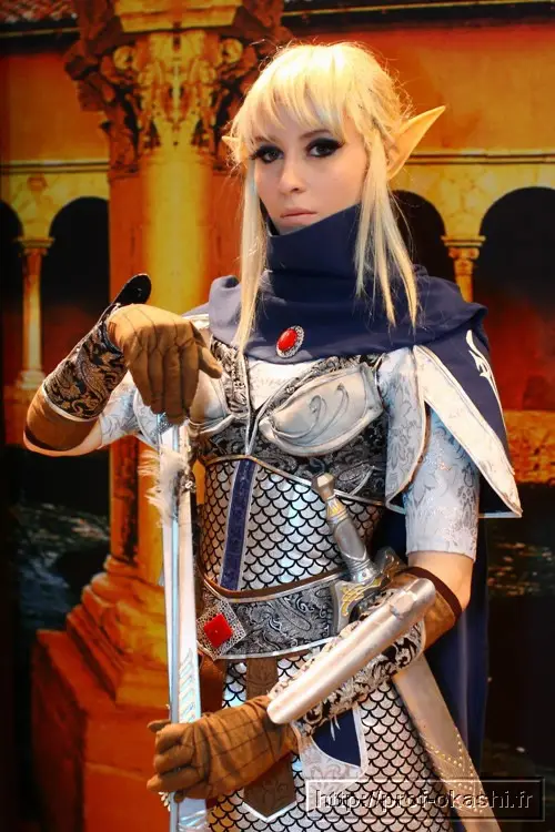 A person in detailed fantasy armor with pointed ears, holding a sword, stares directly at the camera with a neutral…
