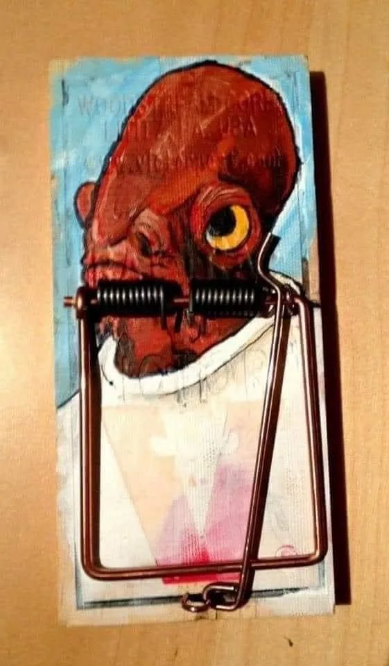 A painted portrait of a red-skinned humanoid figure with a large yellow eye is depicted on a piece of cardboard, with a…