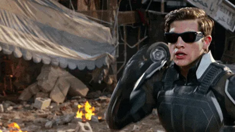 A three-frame sequence shows a man in a black tactical suit and sunglasses, initially looking concerned while raising his…