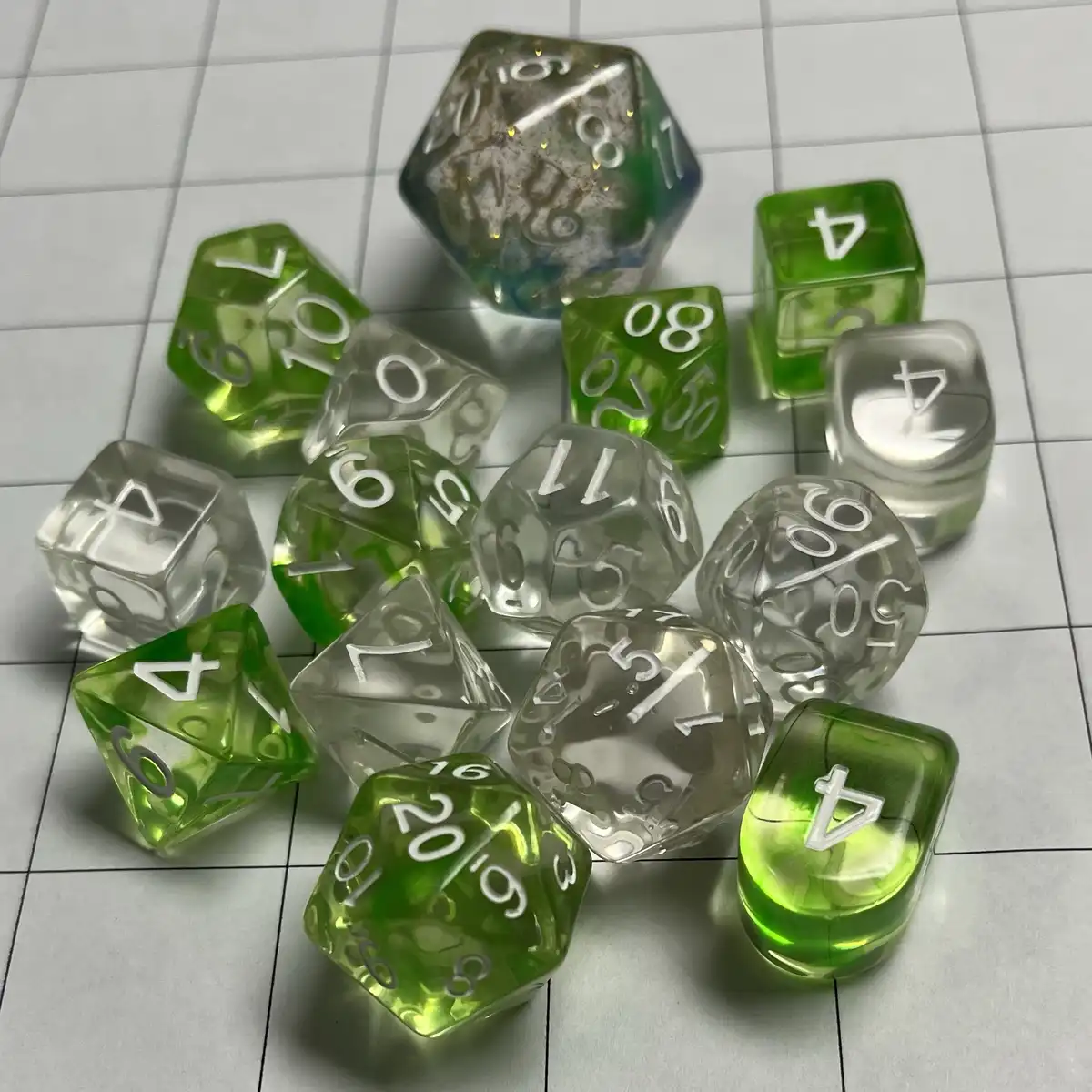 A collection of translucent green and clear polyhedral dice, including d4, d6, d8, d10, d12, and d20, are scattered on a…