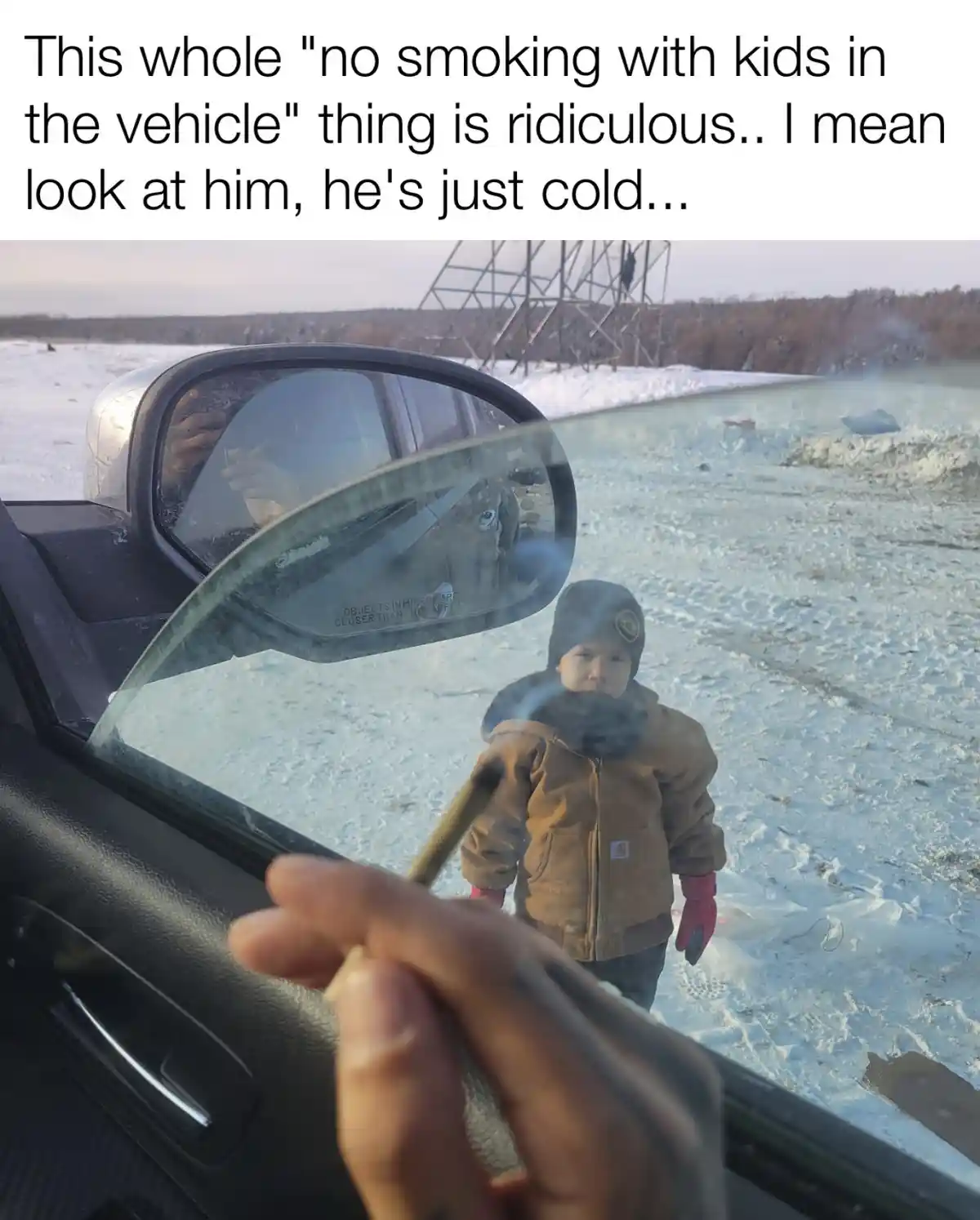 A person is seen smoking a cigarette from inside a car, with the reflection in the side mirror showing their hand holding…