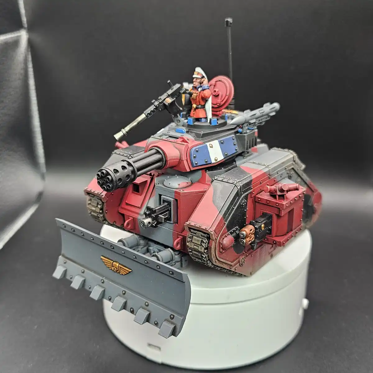 A highly detailed, red and grey painted miniature tank model with multiple weapons, including a large multi-barrel gun and a…