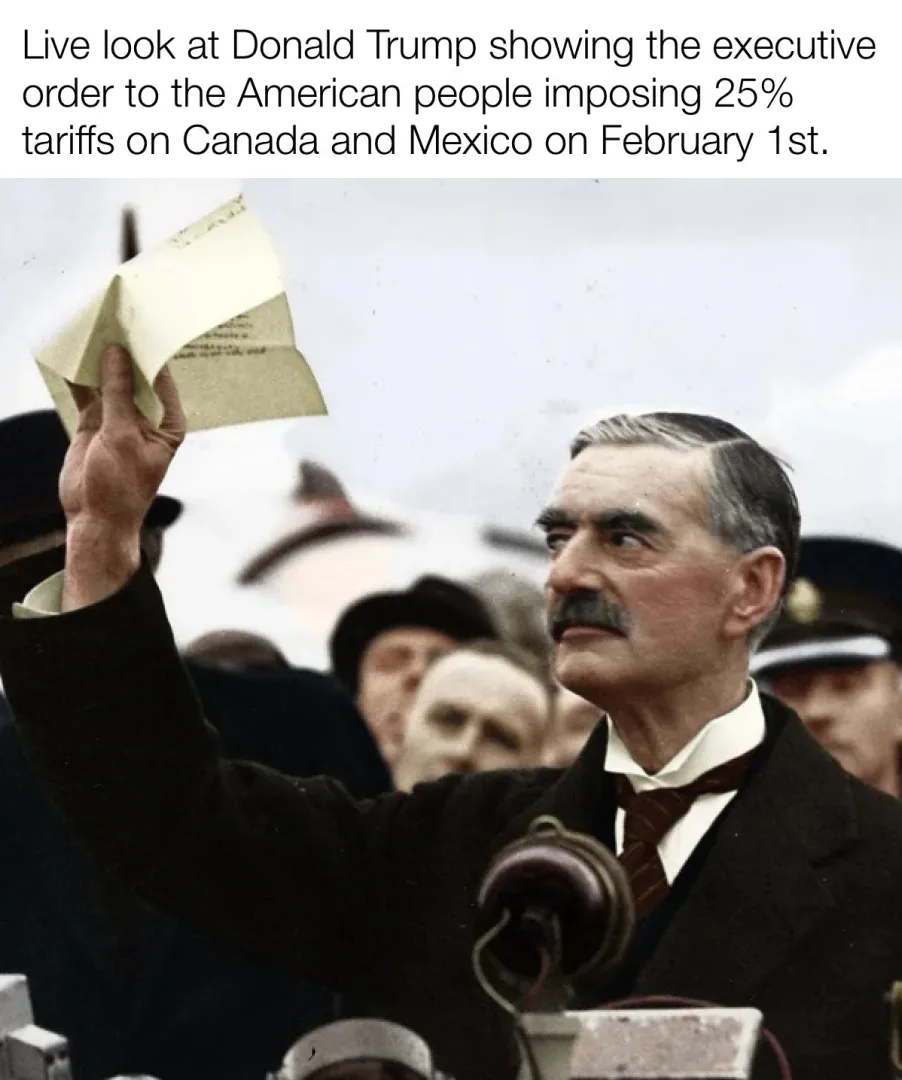 A man with a mustache in a suit and tie holds up a folded piece of paper while standing at a podium with a vintage…