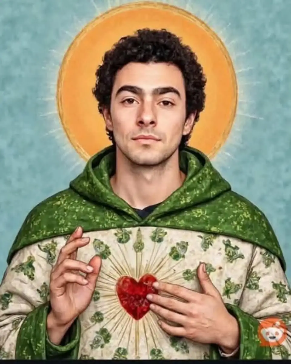 A man with curly dark hair, wearing a green hooded robe over a white tunic with green shamrock patterns, holds a glowing red…