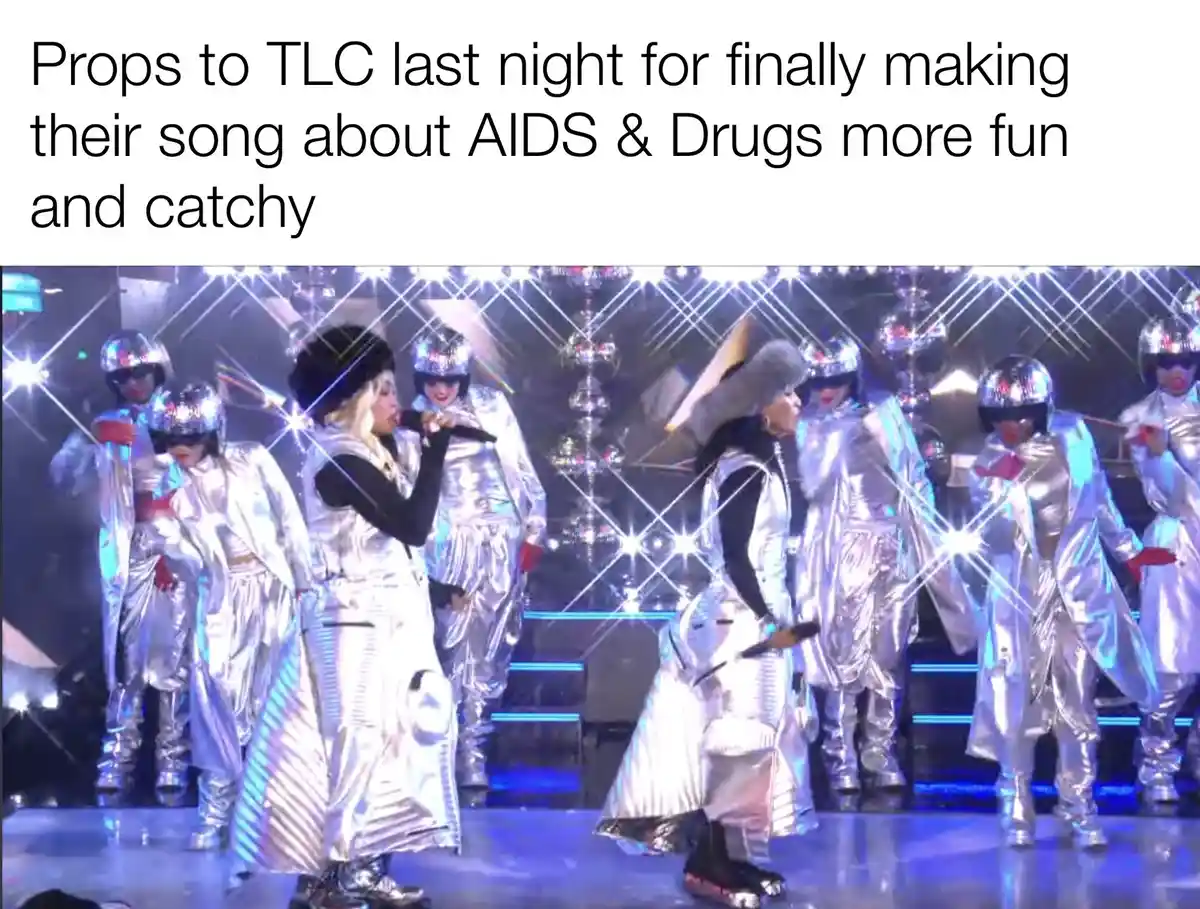 The image shows the R&B group TLC performing on stage in shiny silver outfits with matching helmets and red gloves…