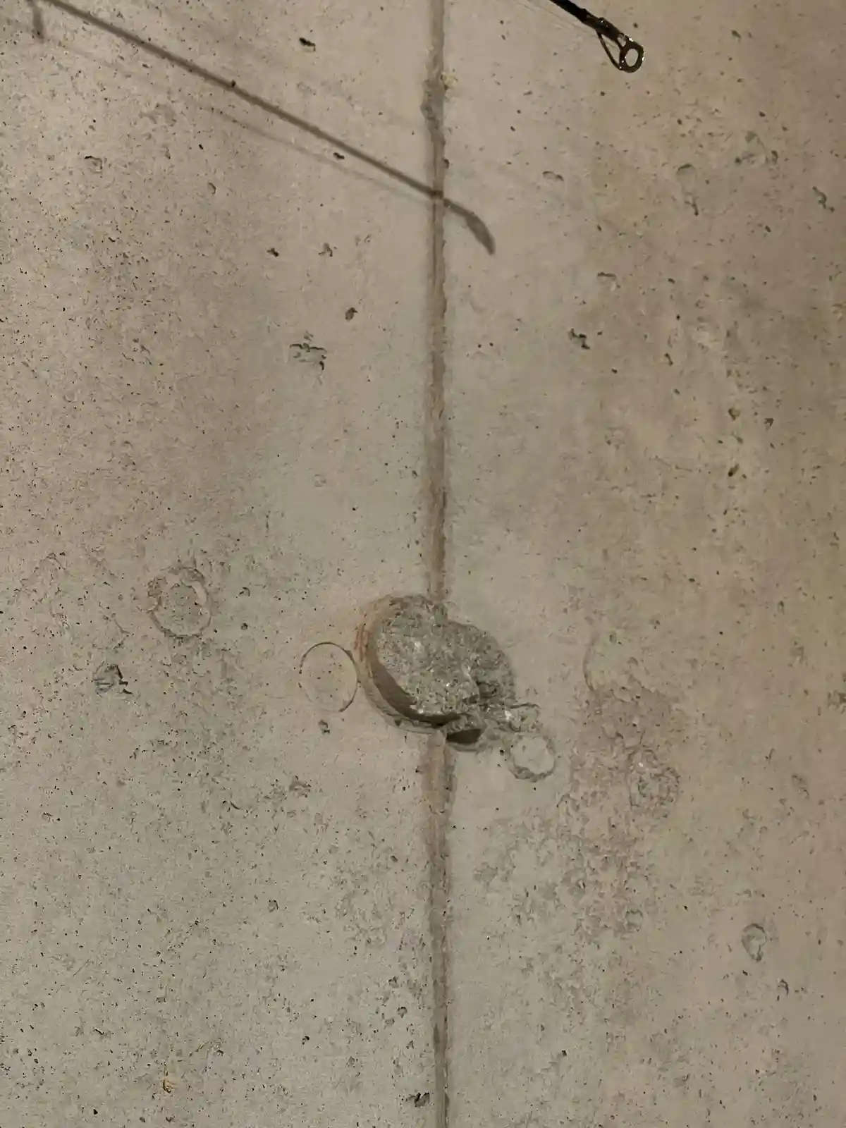A close-up photo shows a rough, unfinished concrete wall with a visible seam down the middle. At the seam, there's a…