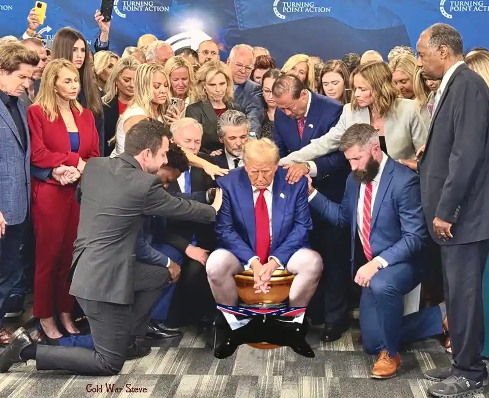 A man in a blue suit and red tie sits in a golden bowl with his head bowed, surrounded by a crowd of people placing their…