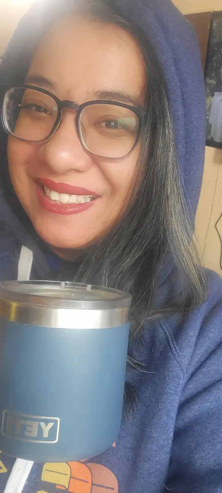 A person wearing glasses and a blue hoodie smiles while holding a blue YETI tumbler. The overlaid text reads 'i'm not lazy…