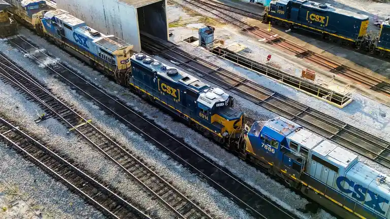 An aerial photo shows multiple CSX freight trains on parallel tracks in a rail yard, with locomotives numbered 7823, 6914…