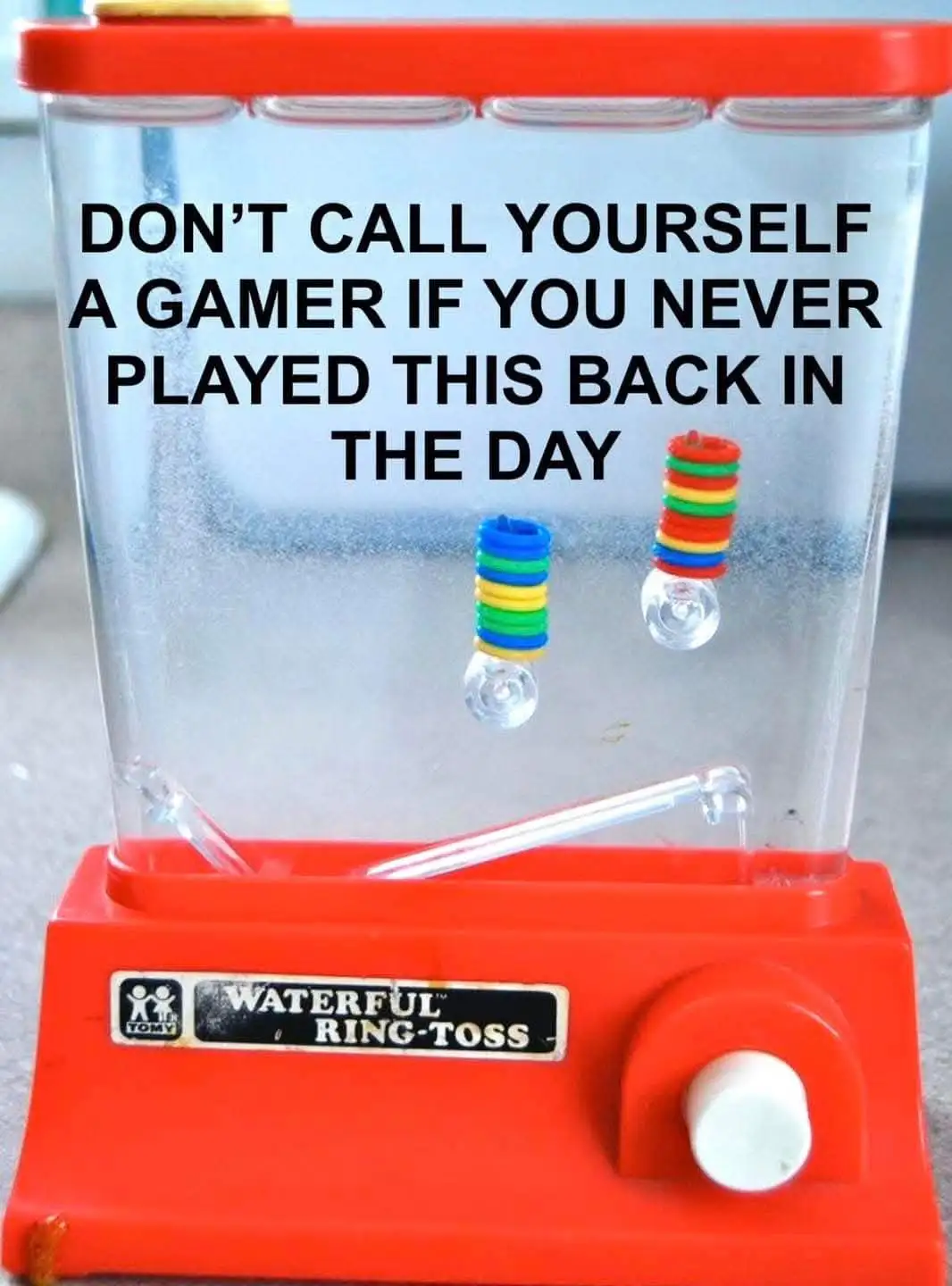 A red and clear plastic Tomy 'Waterful Ring-Toss' toy with colorful rings stacked on glass orbs inside. The overlaid text…