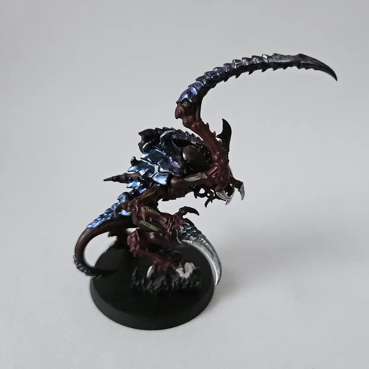 A highly detailed, painted miniature of a fantasy creature resembling a dragon or wyvern, featuring dark red and metallic…