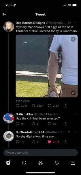 A screenshot of a Twitter thread shows a photo of a person in a white t-shirt and khaki shorts standing next to a statue…