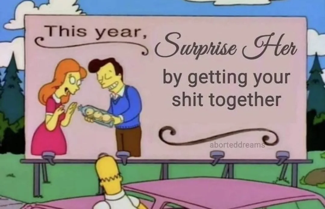 A billboard from The Simpsons shows a man in a blue sweater presenting a baby bottle to a woman in a pink dress, with the…