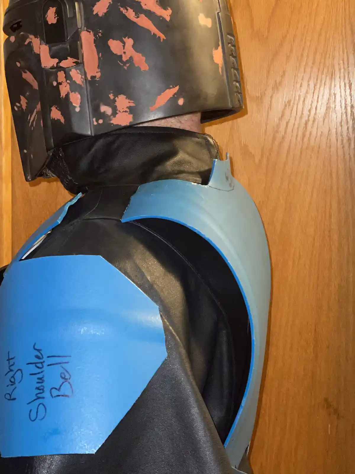 A close-up of a person in a Boba Fett costume, showing the shoulder armor with a blue hexagonal plate labeled 'Right…