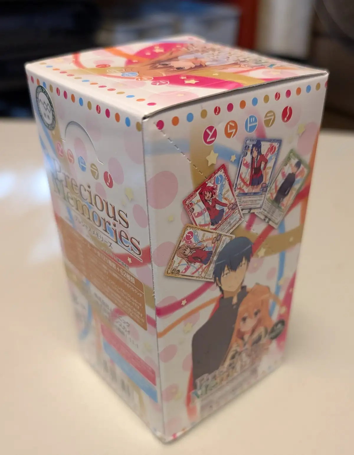 A close-up photo of a 'Precious Memories' trading card game booster box for the anime 'Little Busters!', featuring colorful…
