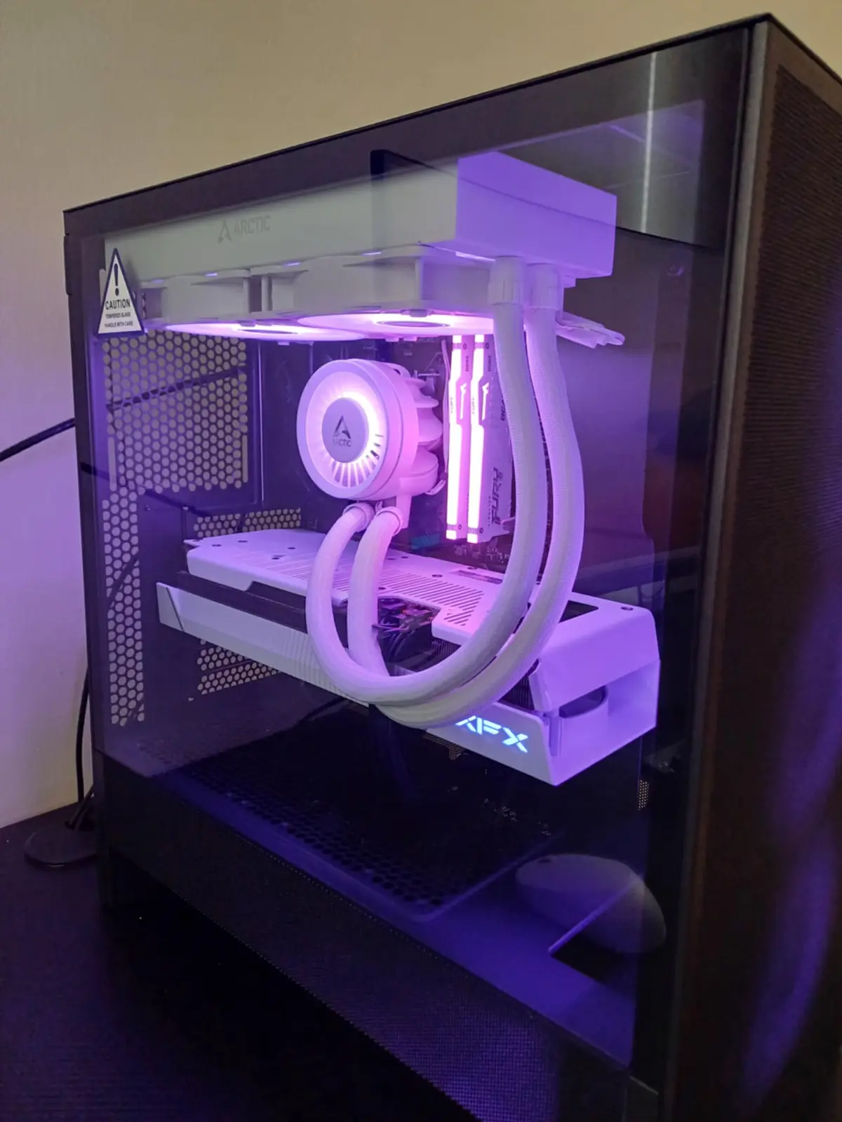 A custom-built PC with a white Arctic liquid cooling system and purple LED lighting inside a transparent case, featuring a…