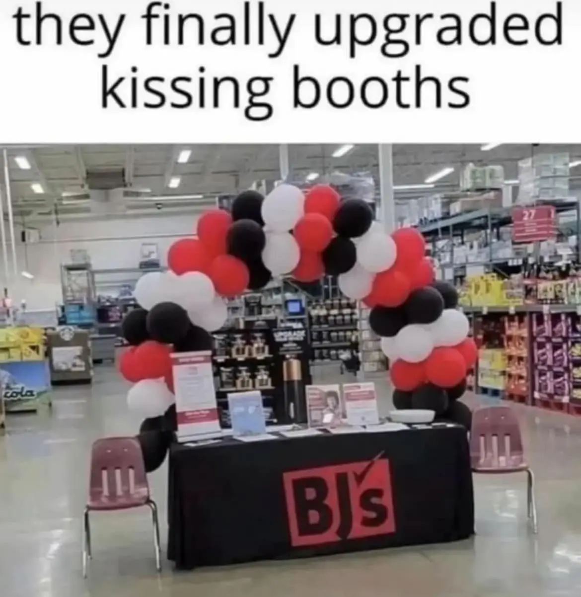 A photo of a table set up inside a BJ's Wholesale Club store, decorated with red, white, and black balloons arranged in an…