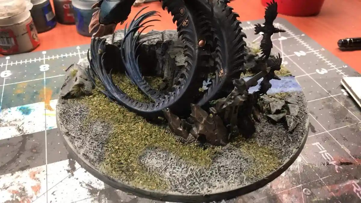 A highly detailed, painted miniature model of a dark, serpentine creature with spiked, segmented body and feathered wings…