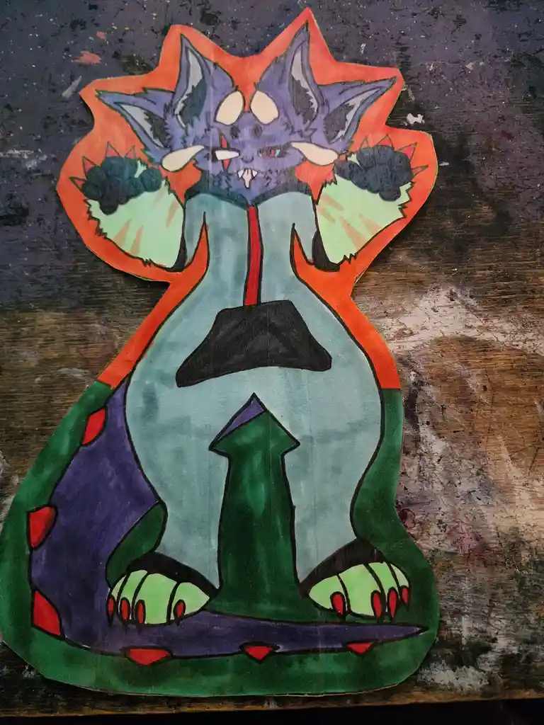 A hand-drawn, colorful paper cutout of a cartoonish purple monster with sharp teeth, claws, and a green arrow-shaped chest…