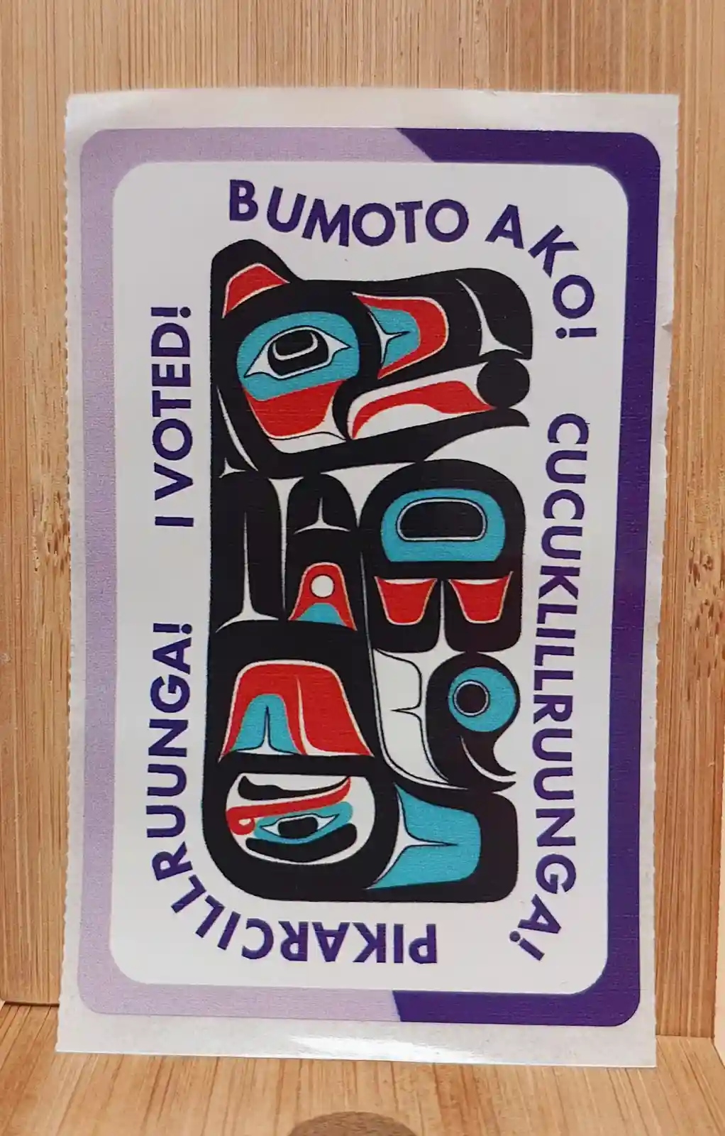 A sticker with a stylized Indigenous Northwest Coast totem pole design featuring red, black, and teal colors. The text…