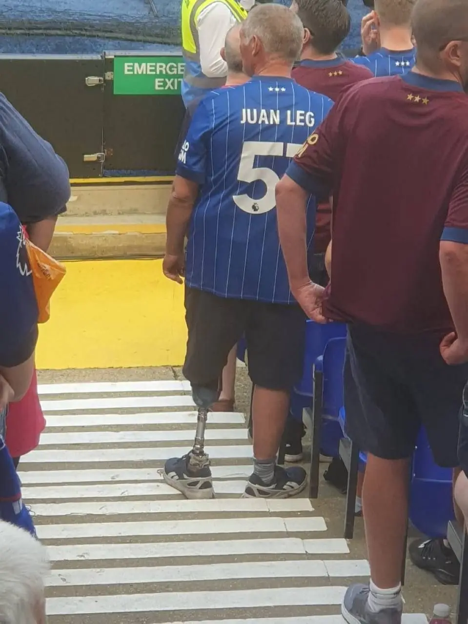 A man with a prosthetic leg stands on a zebra crossing wearing a blue football jersey with 'JUAN LEG' and the number 5…
