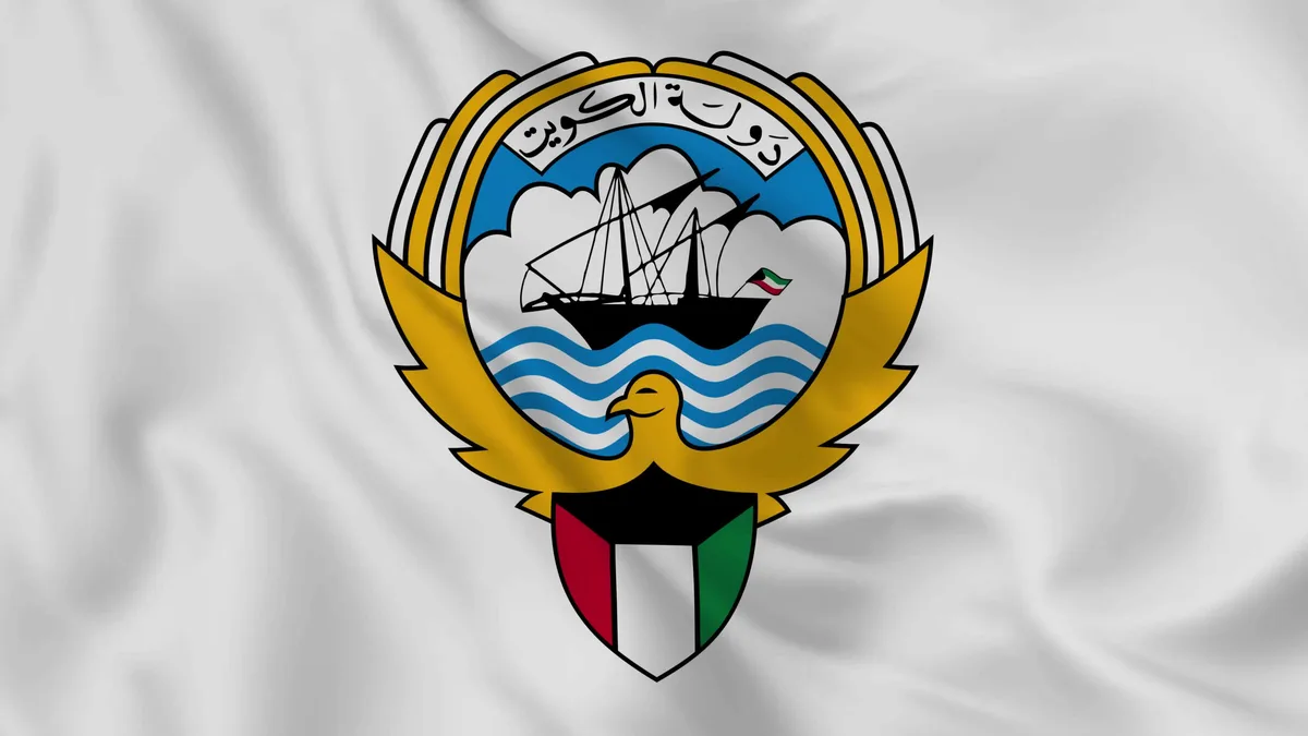 The image displays the flag of Kuwait, featuring a central emblem on a white field. The emblem includes a golden eagle, a…