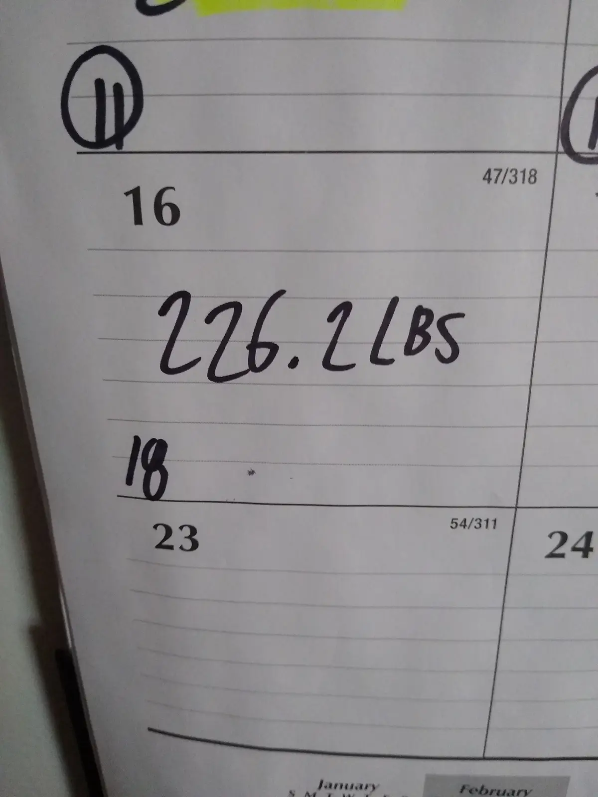 A close-up of a handwritten weight tracking calendar shows the date '16' with '226.2 LBS' written below it, and the date…