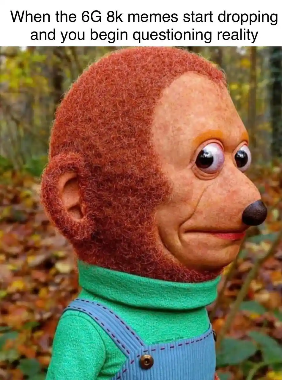 A close-up of a puppet-like figure with reddish-brown fuzzy hair, large googly eyes, and a black nose, wearing a green…