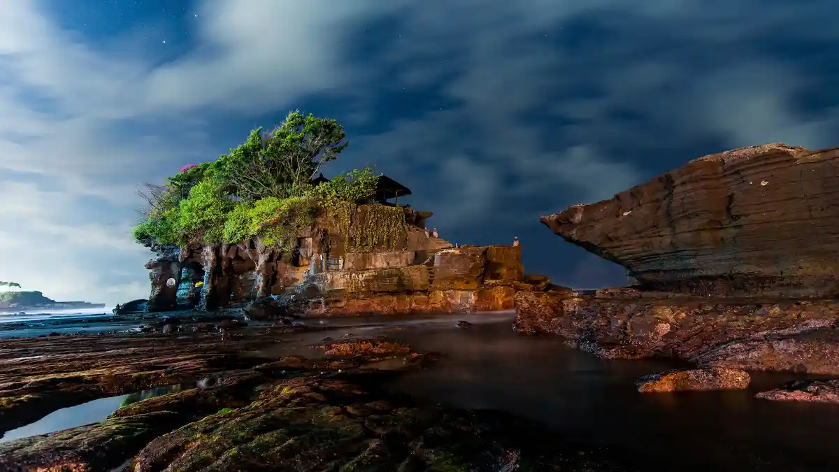 Tanah Lot, a Balinese sea temple, is one of seven temples built along Bali's coastline to ward off evil. Fringed by…