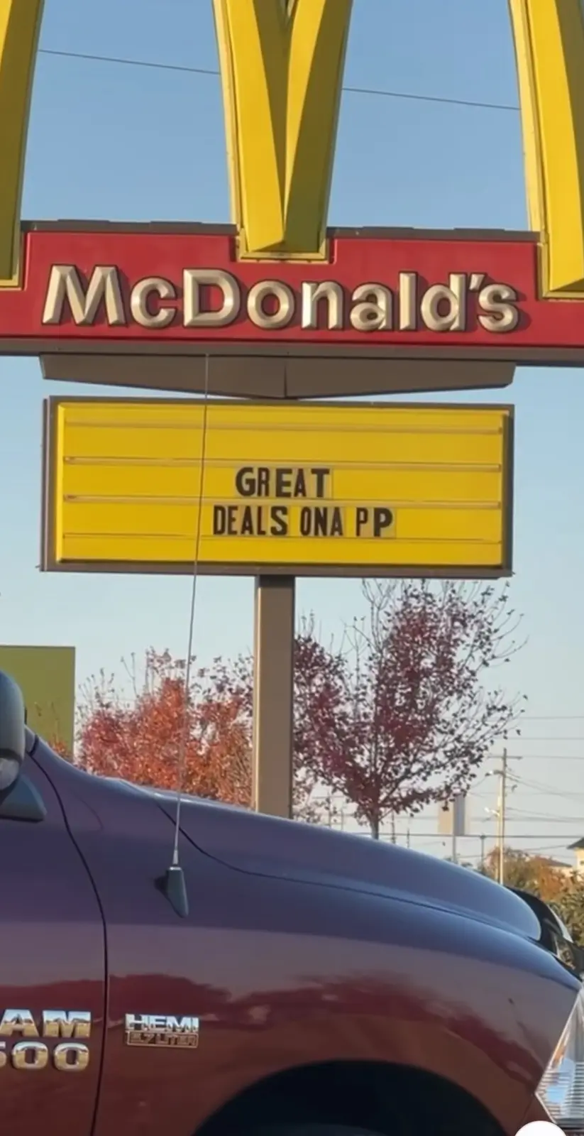 A McDonald's sign with a yellow marquee board below it that reads 'GREAT DEALS ONA PP'. The image shows the top of a maroon…