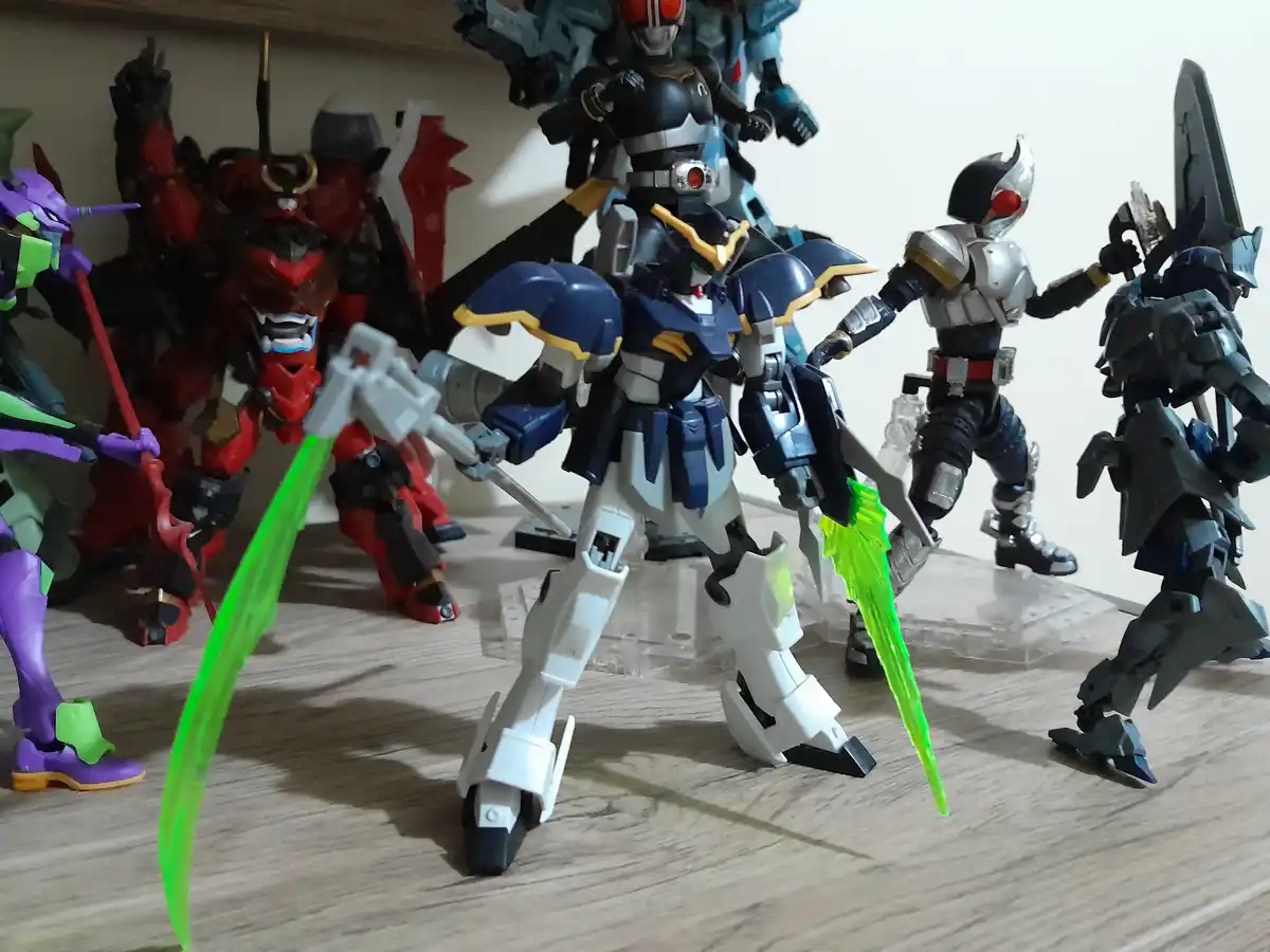 A collection of anime action figures, including a blue and white Gundam with glowing green blades, a red armored figure, a…