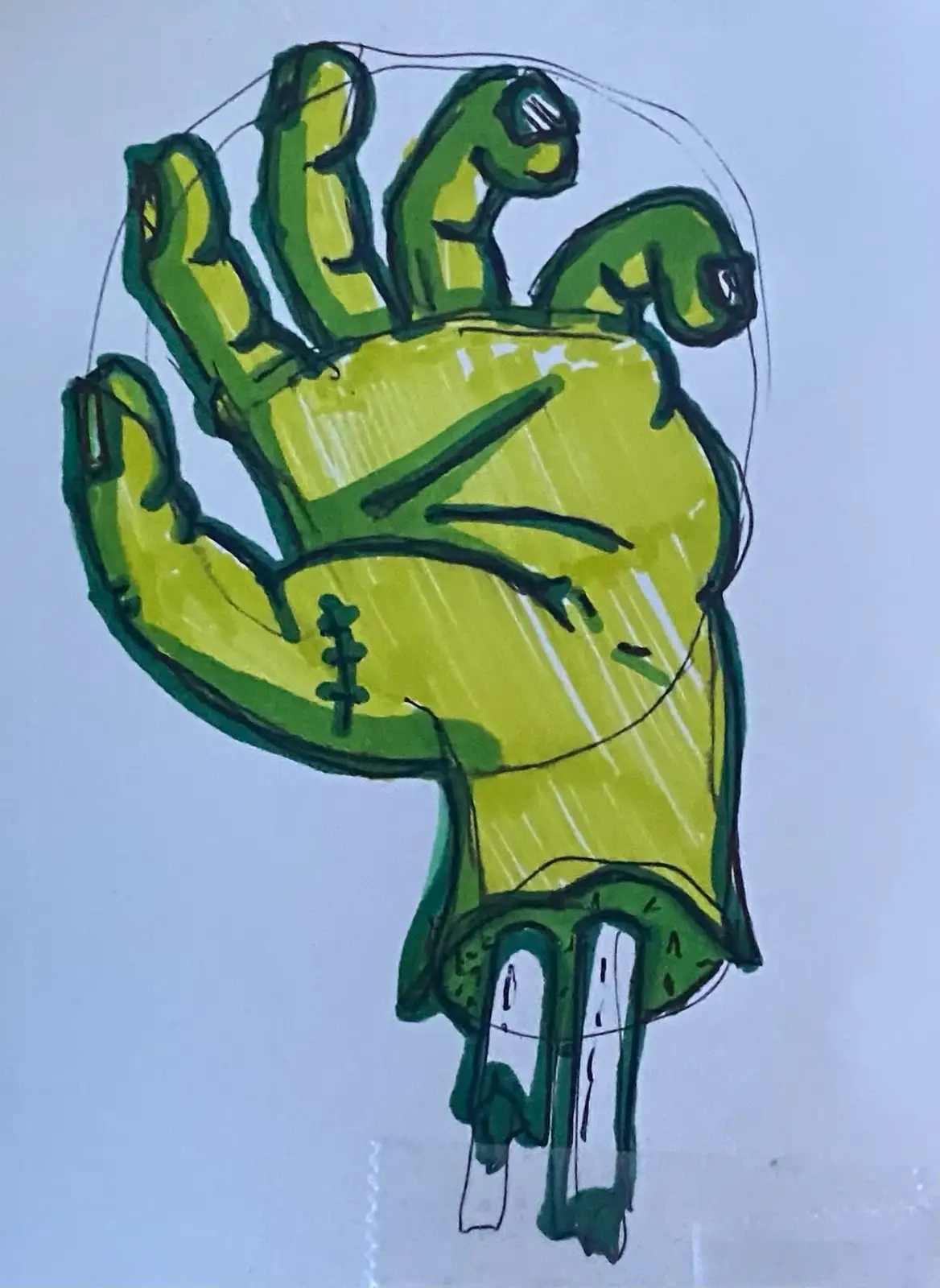 A hand-drawn, crudely colored illustration depicts a green, zombie-like hand with stitches on the palm, skeletal fingers…