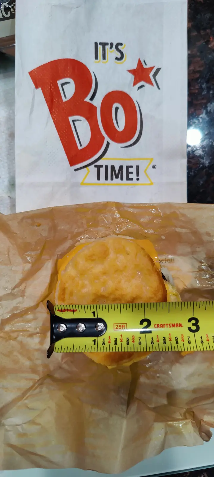 A close-up photo shows a partially unwrapped Burger King 'It's Bo Time!' sandwich with a yellow measuring tape laid across…